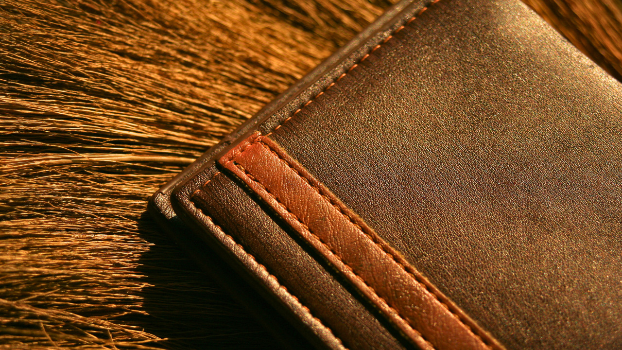 革製の財布が藁の上に置いてある画像